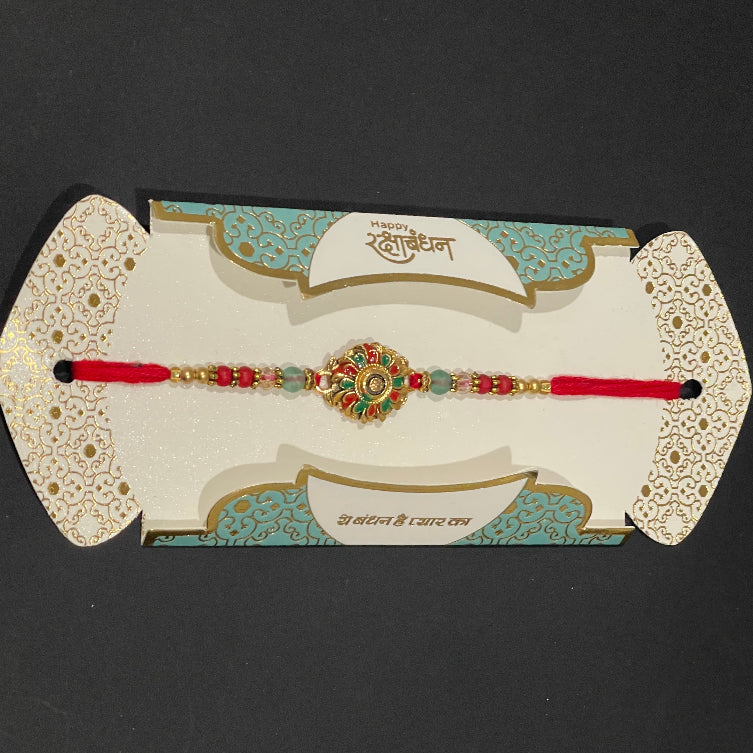Decorative red bracelet with green stones on a decorative card against a black background