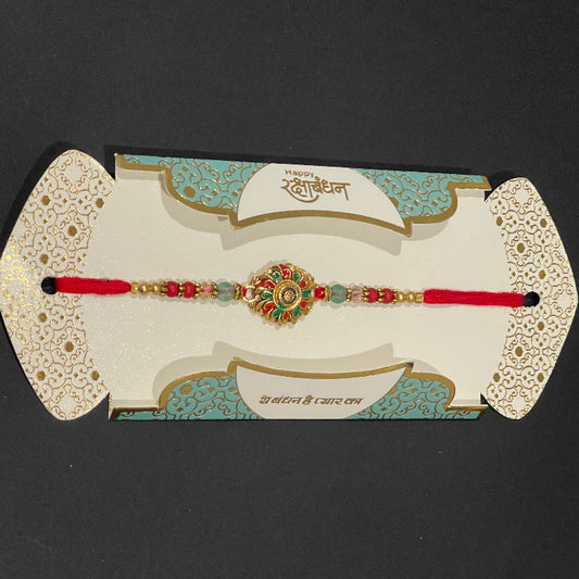 Decorative red bracelet with green stones on a decorative card against a black background