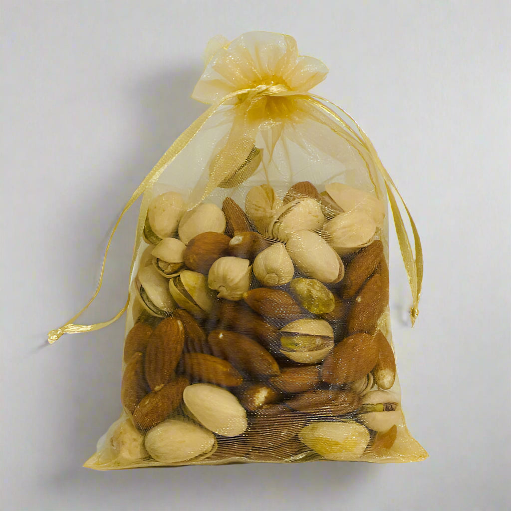 Assorted nuts in a gold drawstring bag on a light gray background
